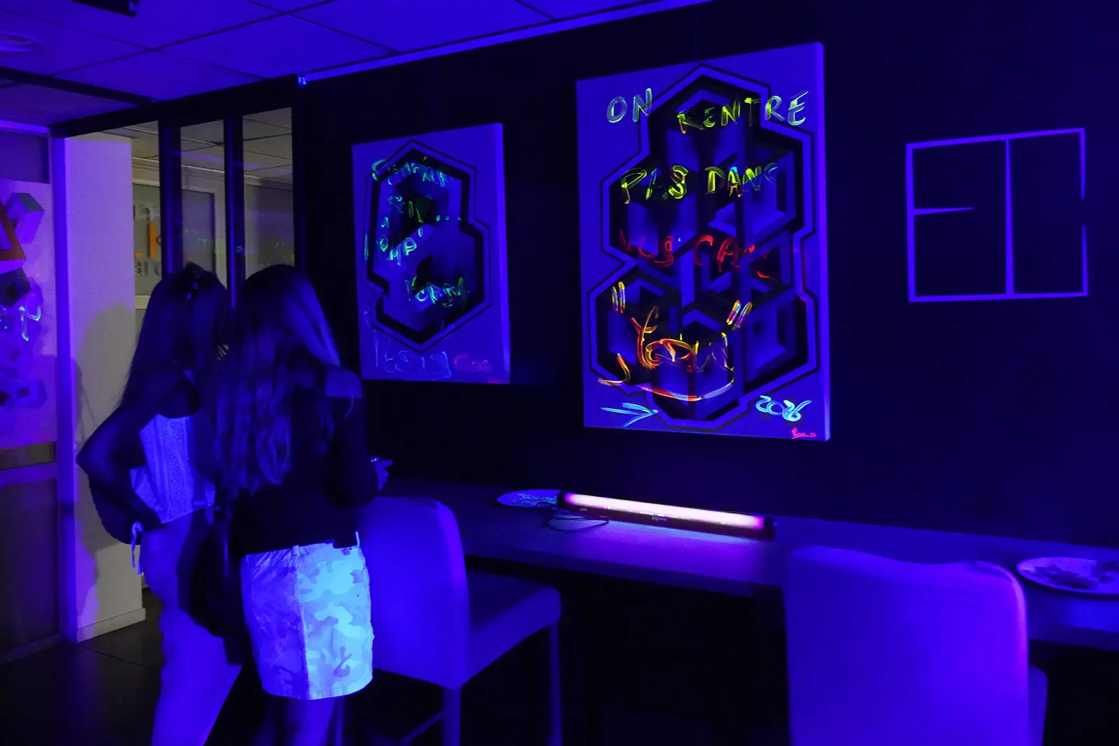 Deux visiteuses observent les peintures fluorescentes