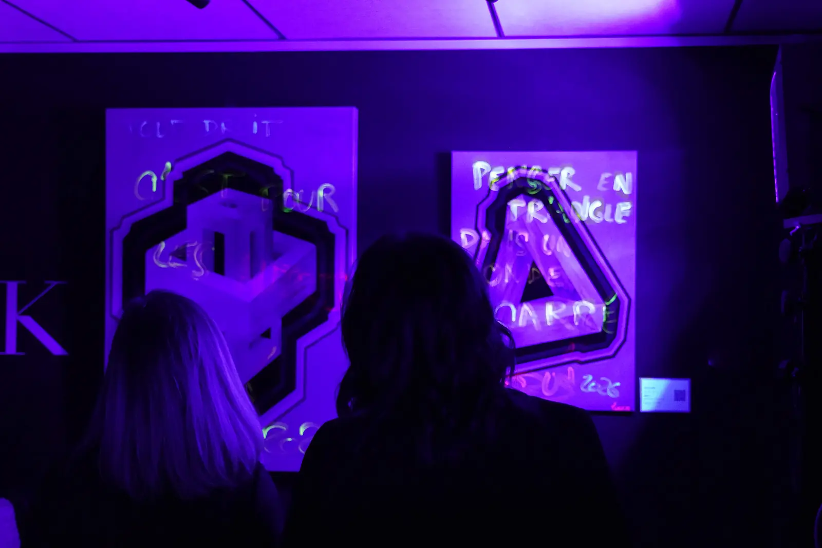 Visiteurs devant les œuvres fluorescentes